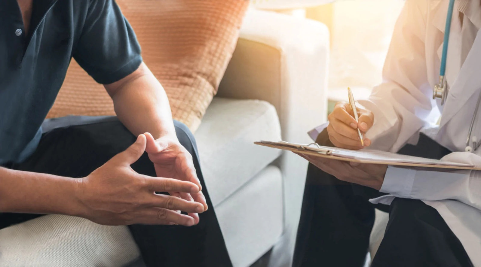 Partial Image of Man Sitting on Couch With Hands Held Together Talking to Doctor About Erectile Dysfunction